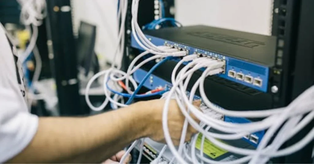 IT technician troubleshooting network by checking ethernet cables on a server switch