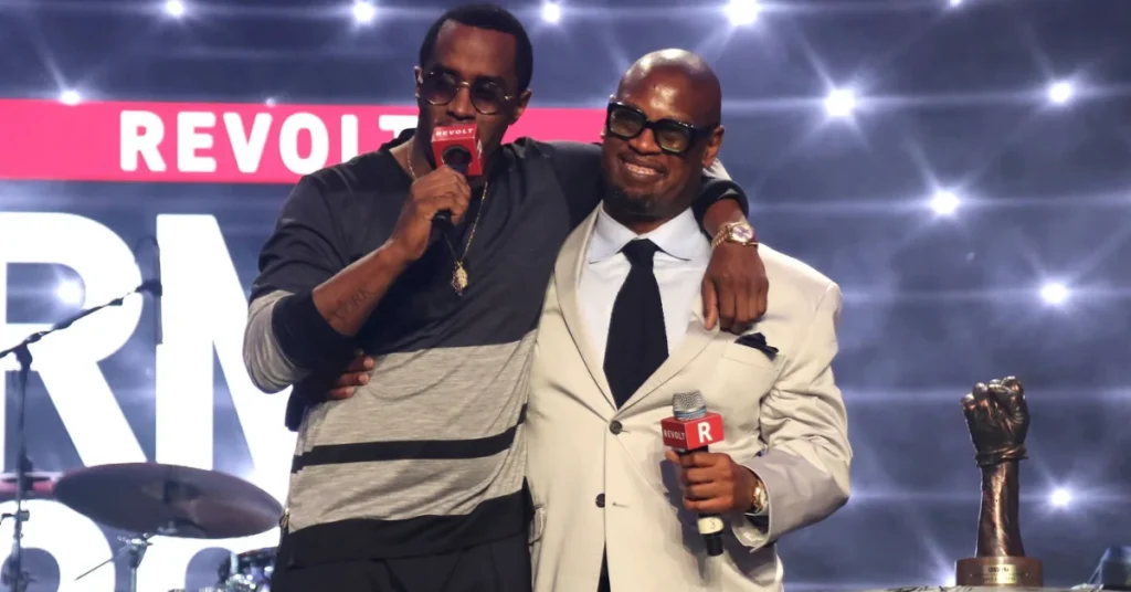 Music executives Sean Combs and Andre Harrell sharing a stage and holding microphones at a REVOLT TV event.