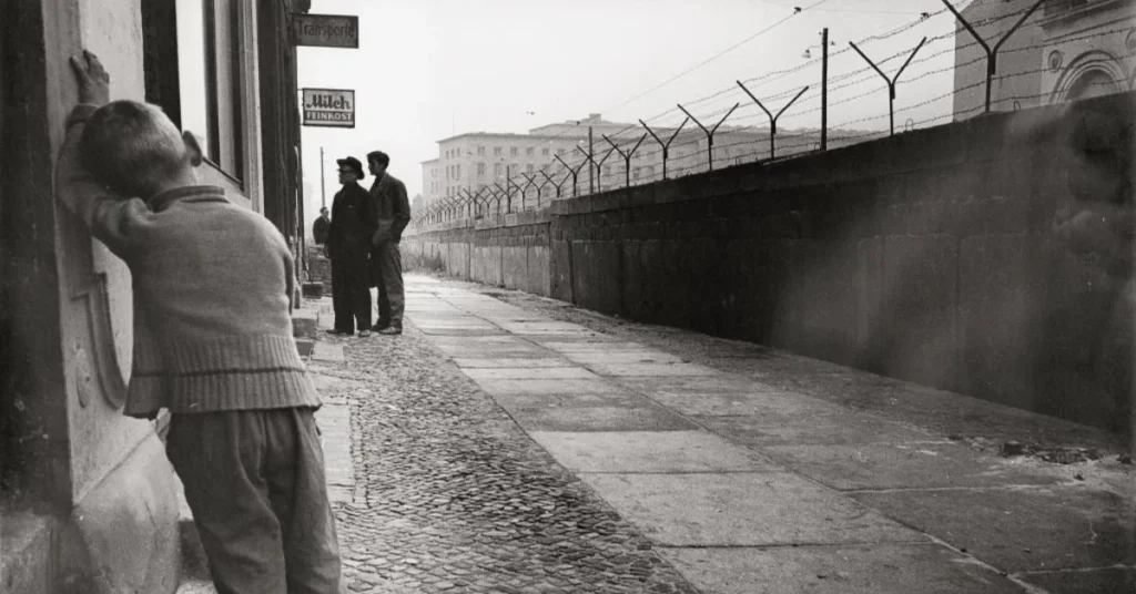 Archival photo of the Berlin Wall and an East German border control watchtower in Berlin during the early 1980s Cold War era.
