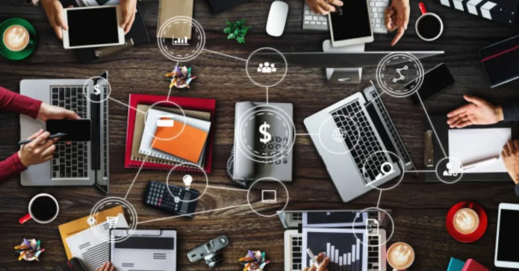 Aerial view of business professionals using laptops tablets and digital devices with connected technology icons