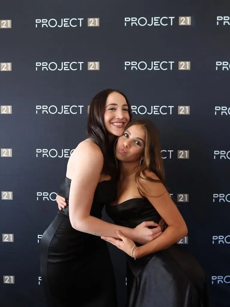 Molly Long hugging a student in front of a Project 21 backdrop.